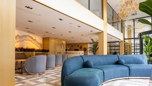 Un hall d’entrée moderne avec un canapé bleu, des fauteuils gris et un comptoir d’accueil.