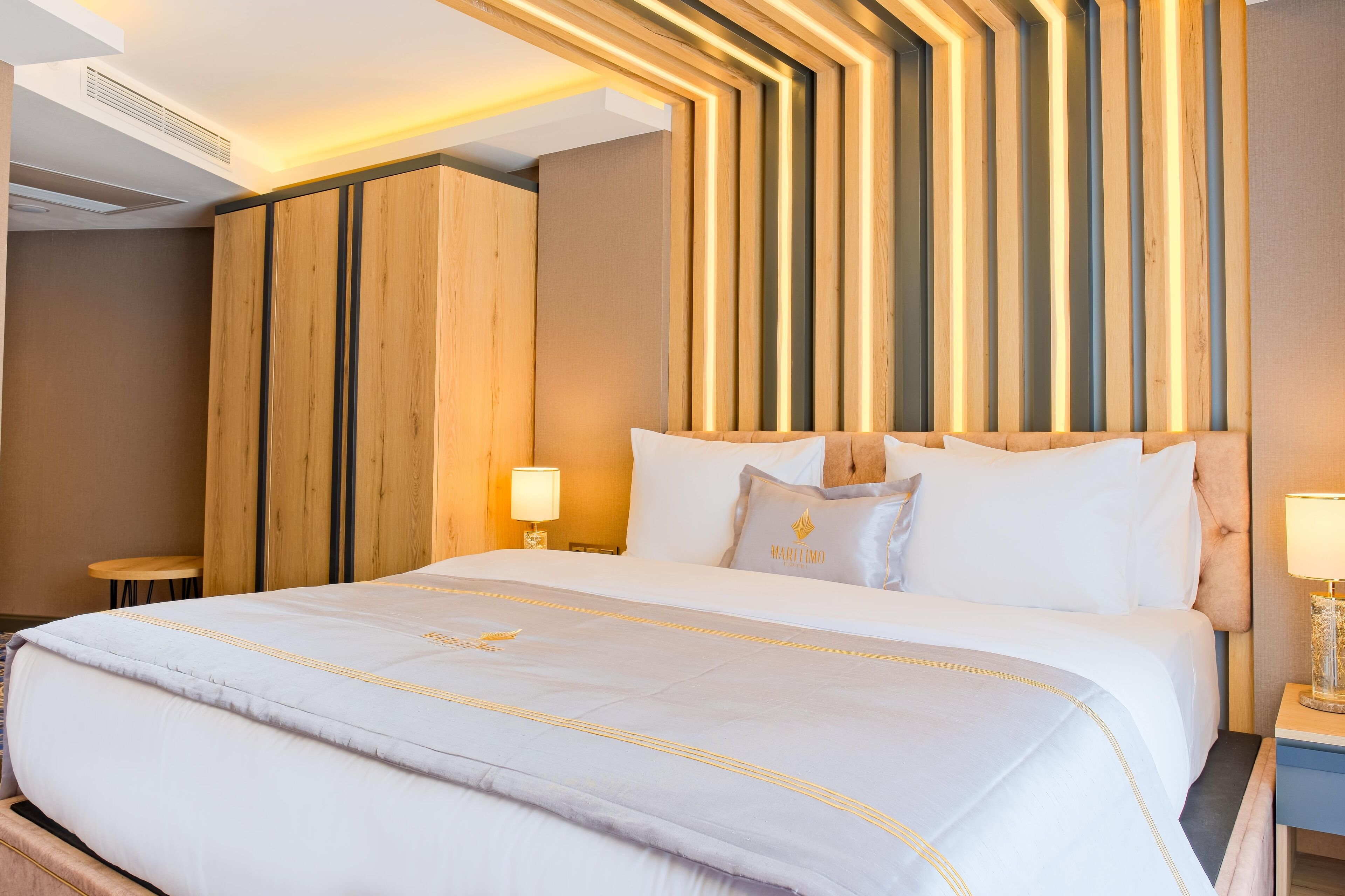 A hotel room with a large bed, wooden headboard, and bedside lamps.