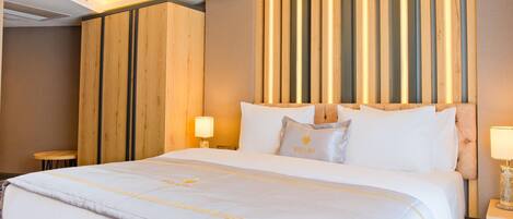 Una habitación de hotel con una cama grande, cabecero de madera y lámparas de noche.