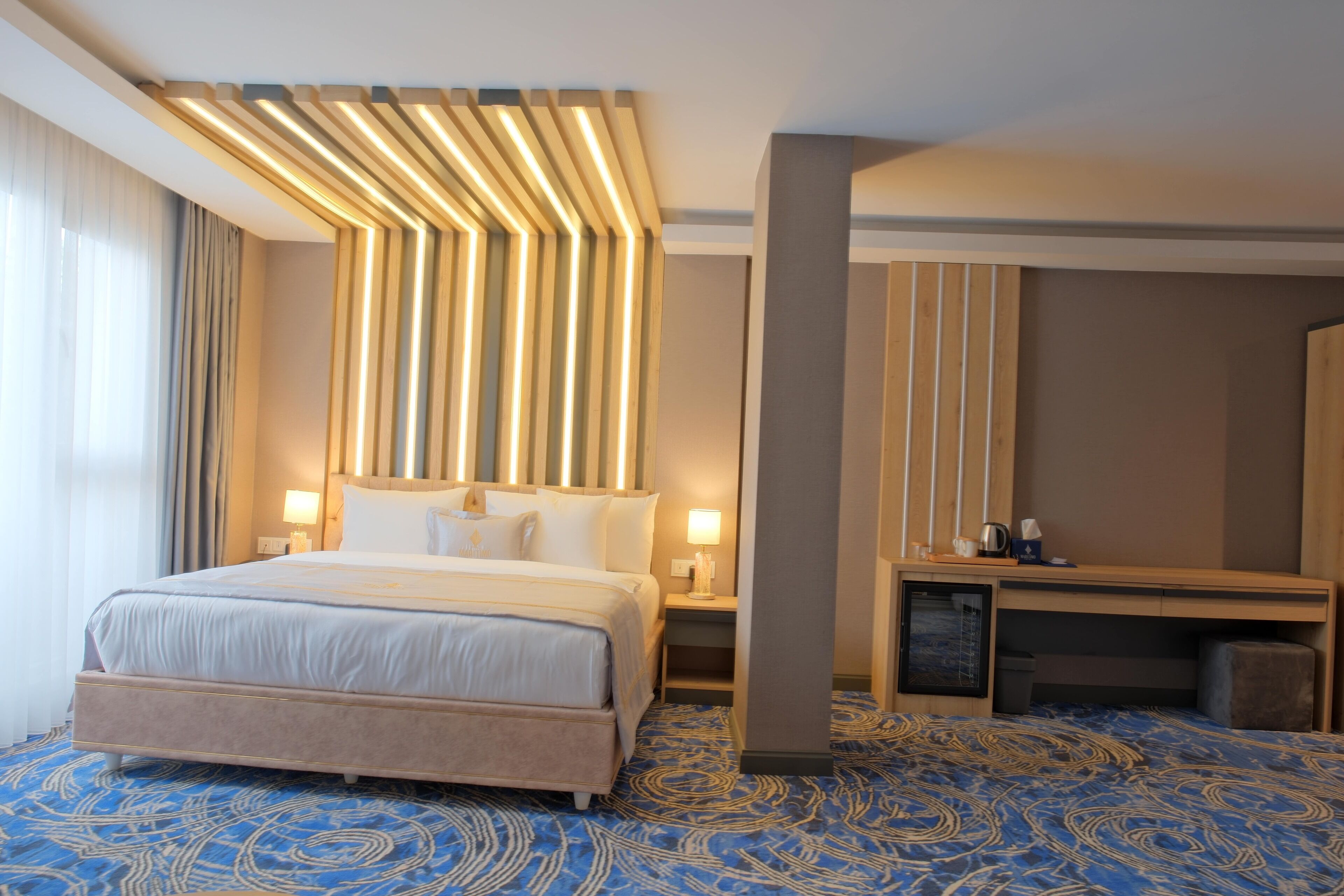 Una habitación de hotel con una cama grande, un escritorio y televisor integrado.
