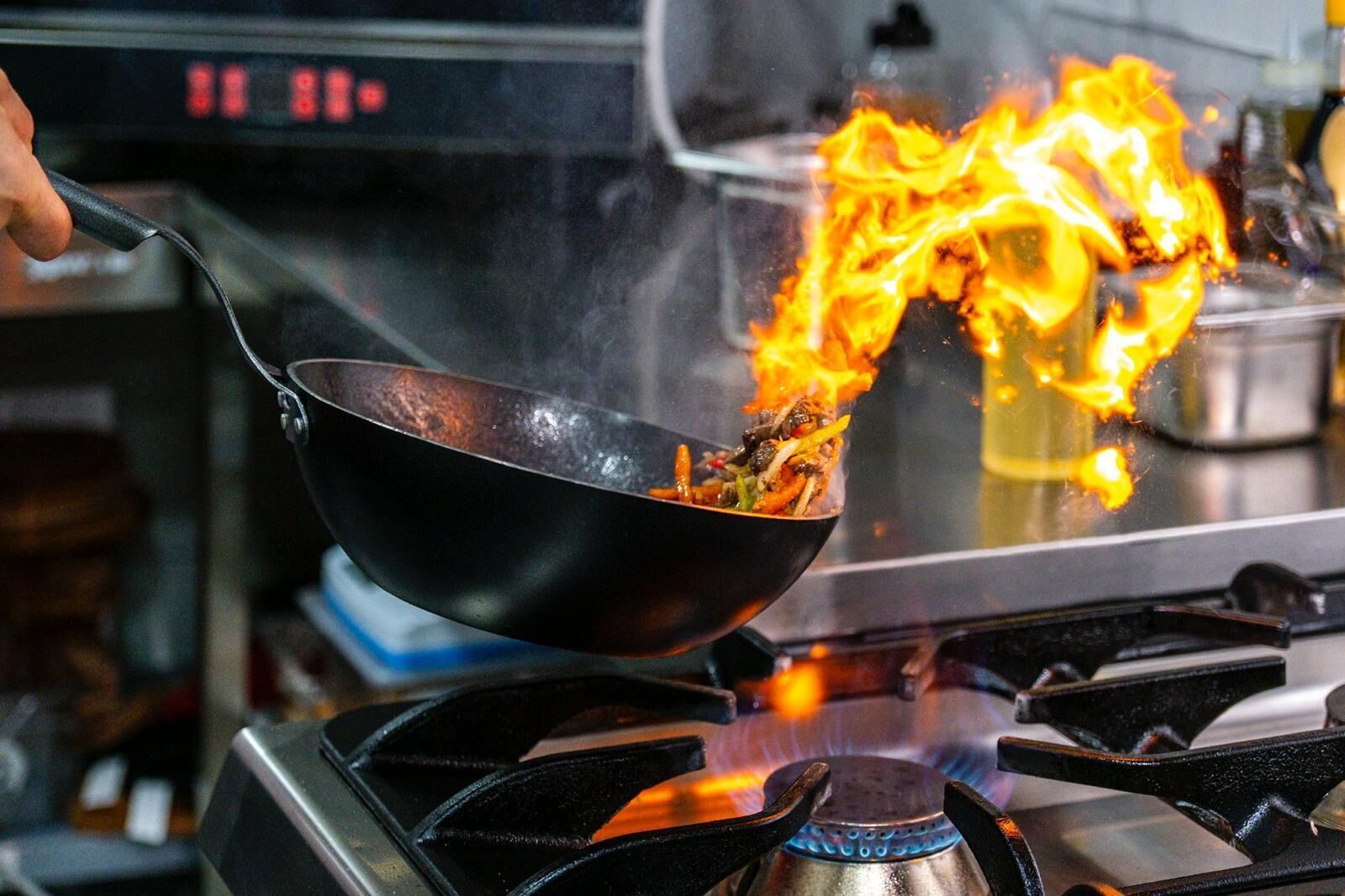 Una olla wok sobre un fogón con llamas.