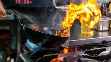 Una olla wok sobre un fogón con llamas.