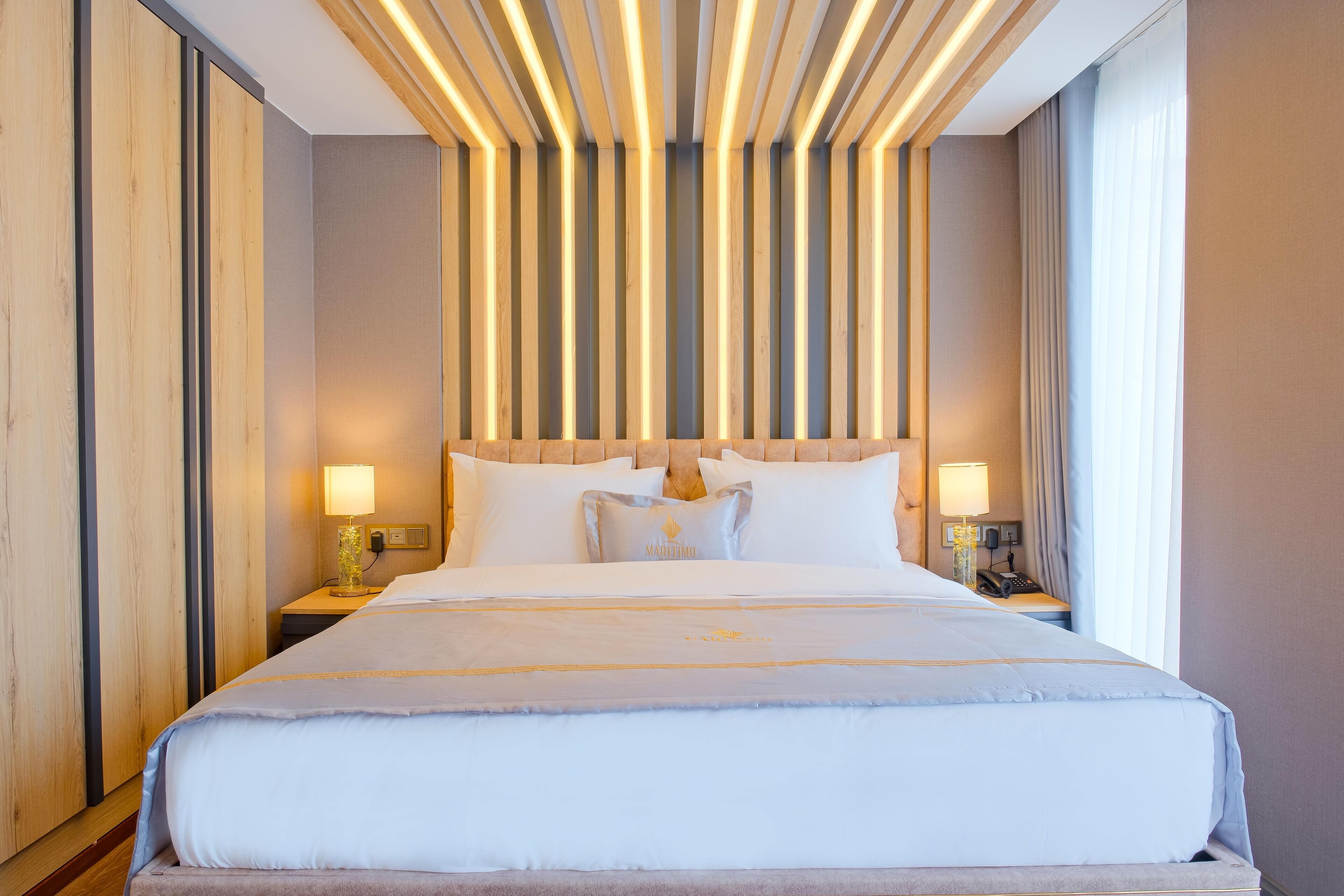 A hotel room with a large bed, wooden panel wall, and two bedside tables with lamps.