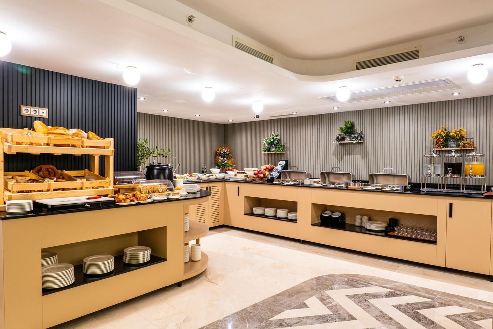 A modern buffet setup with multiple serving stations, a variety of food items, and decorative elements like plants and flowers.