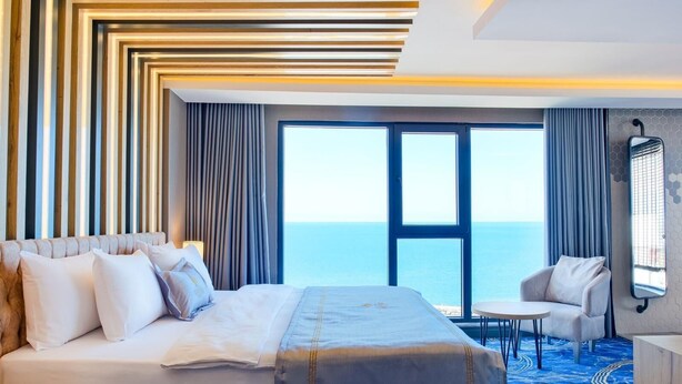 Une chambre d’hôtel avec un grand lit, une petite table, une chaise et une vue sur la mer.
