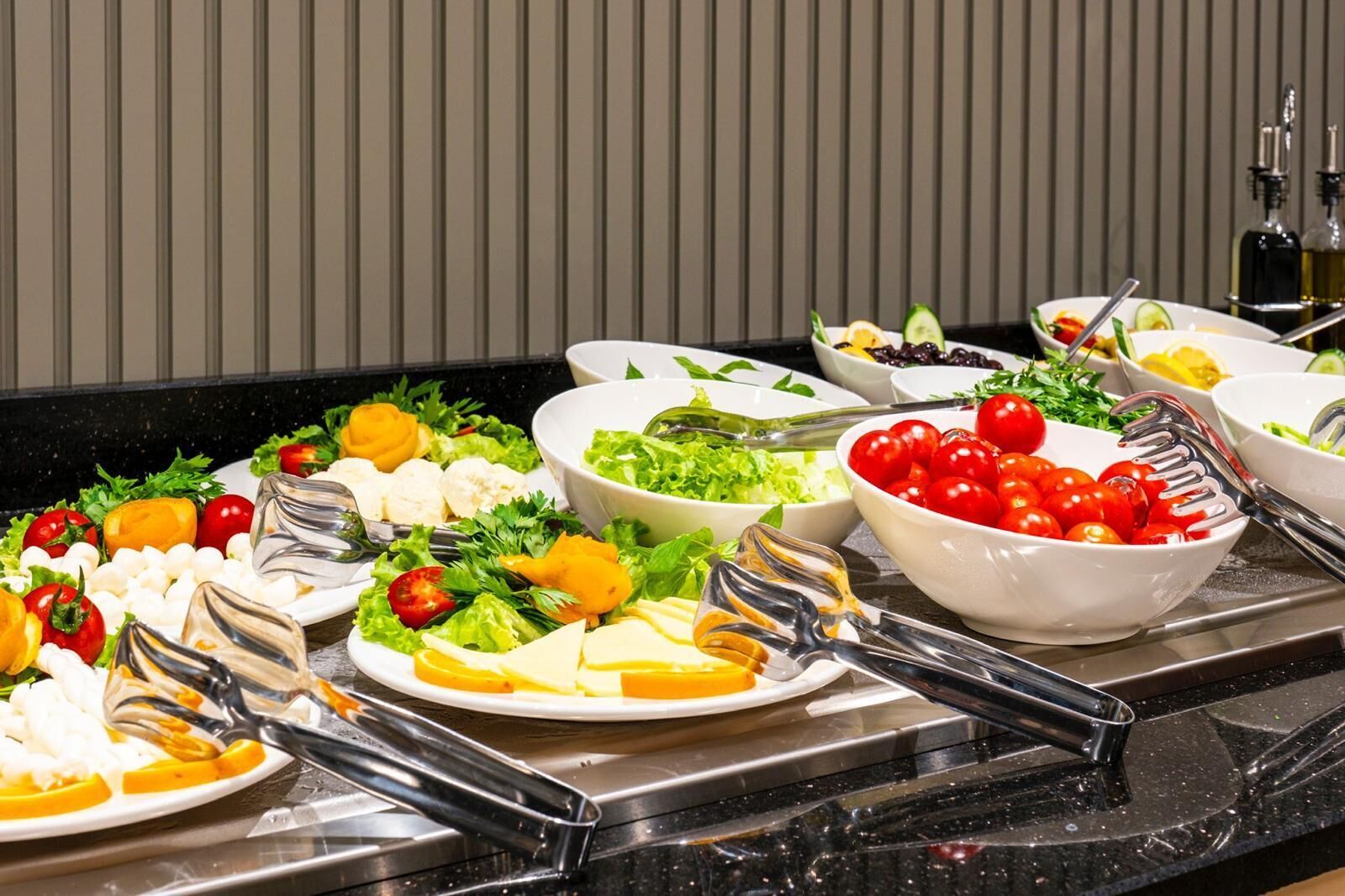 Un bufé con diversos platos, incluyendo ensaladas, frutas y quesos.