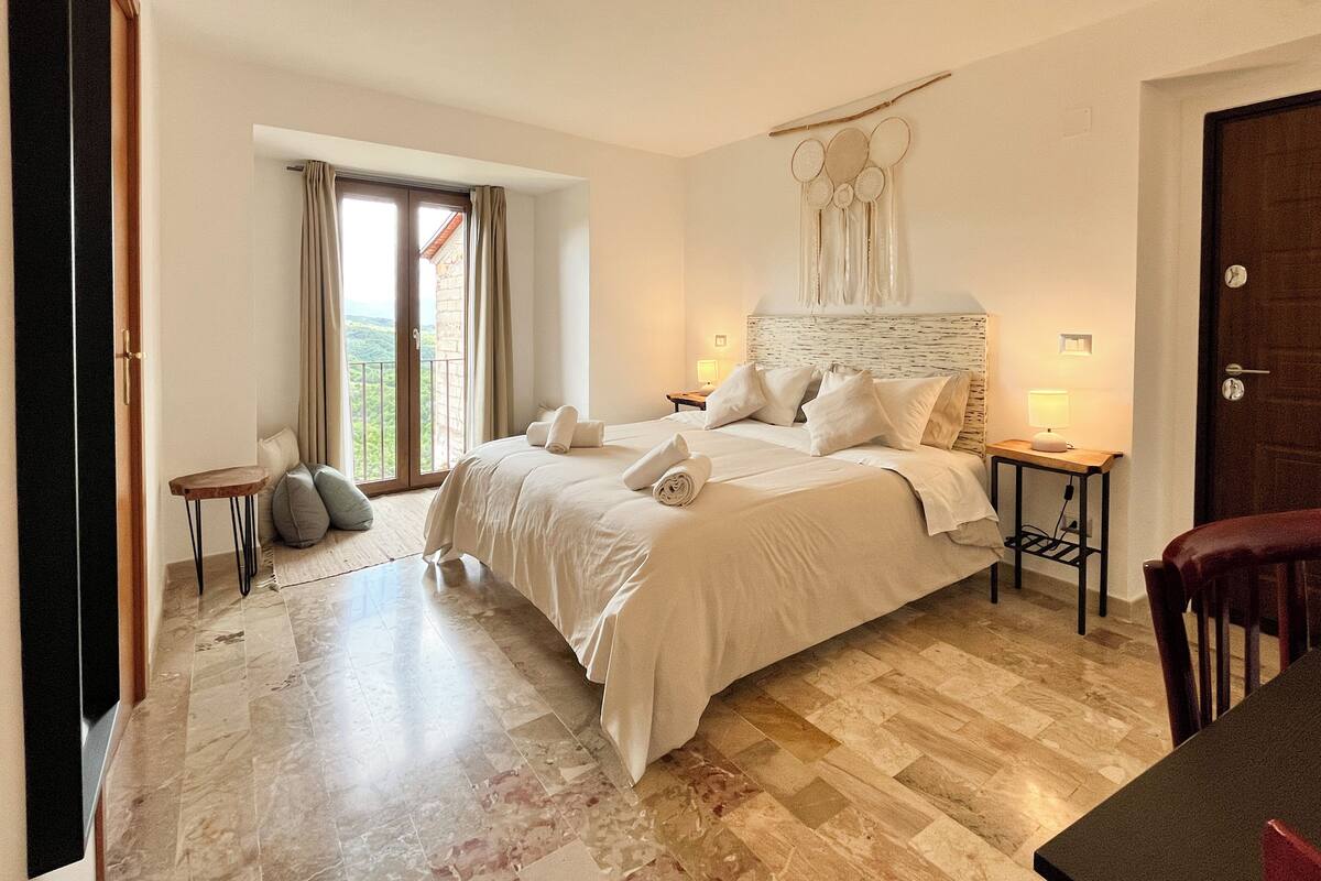 Une chambre à coucher avec un grand lit, une table de chevet, une petite table et une porte.