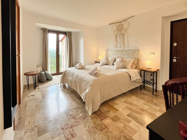 Une chambre à coucher avec un grand lit, une table de chevet, une petite table et une porte.