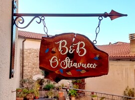 Un letrero colgante con el texto 'B&B O'Stavacco' y hojas decorativas.