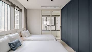 Una habitación de hotel moderna con dos camas, un ventanal grande y vistas a la ciudad.