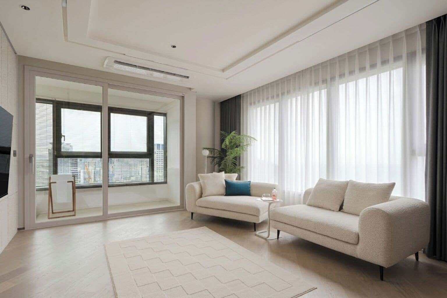 A modern living room with a sofa, a coffee table, a floor lamp, and a large window with curtains.