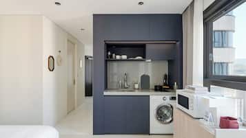 A compact kitchen with a washing machine, microwave, and a small countertop area.