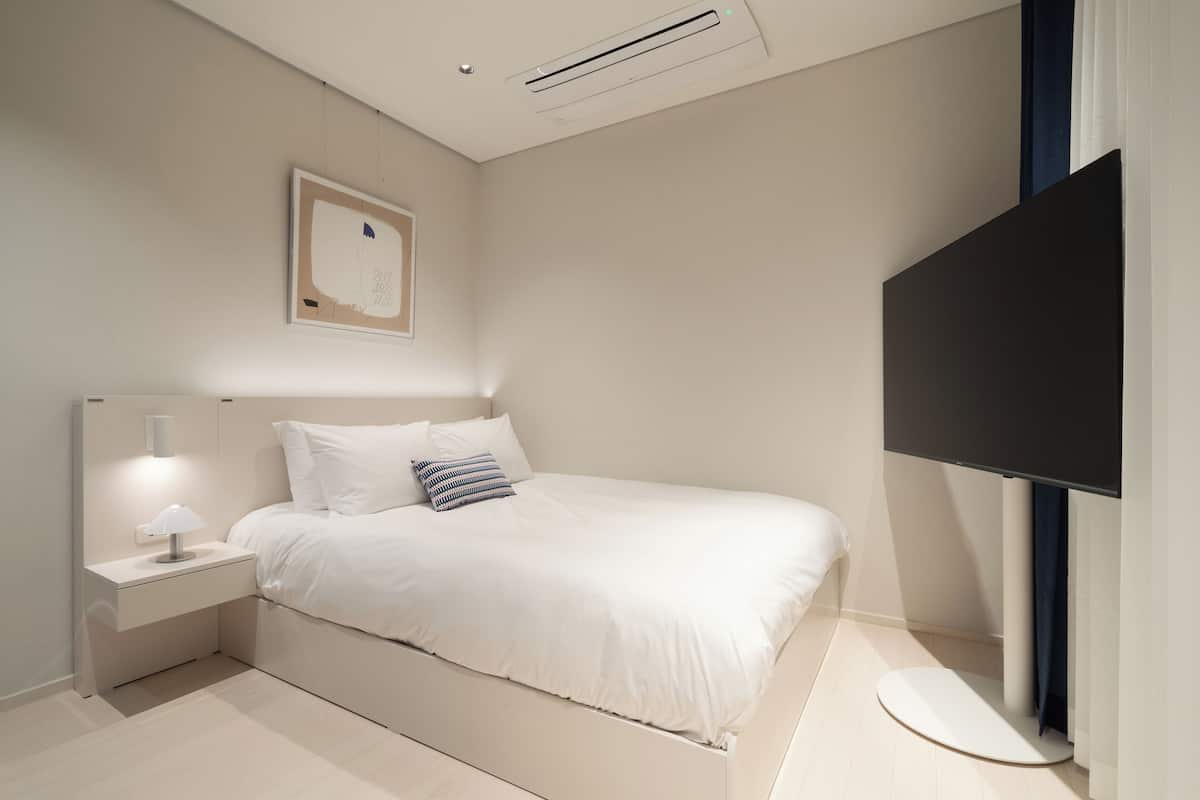 Ein modernes Schlafzimmer mit Bett, Nachttisch und Flachbildfernseher.
