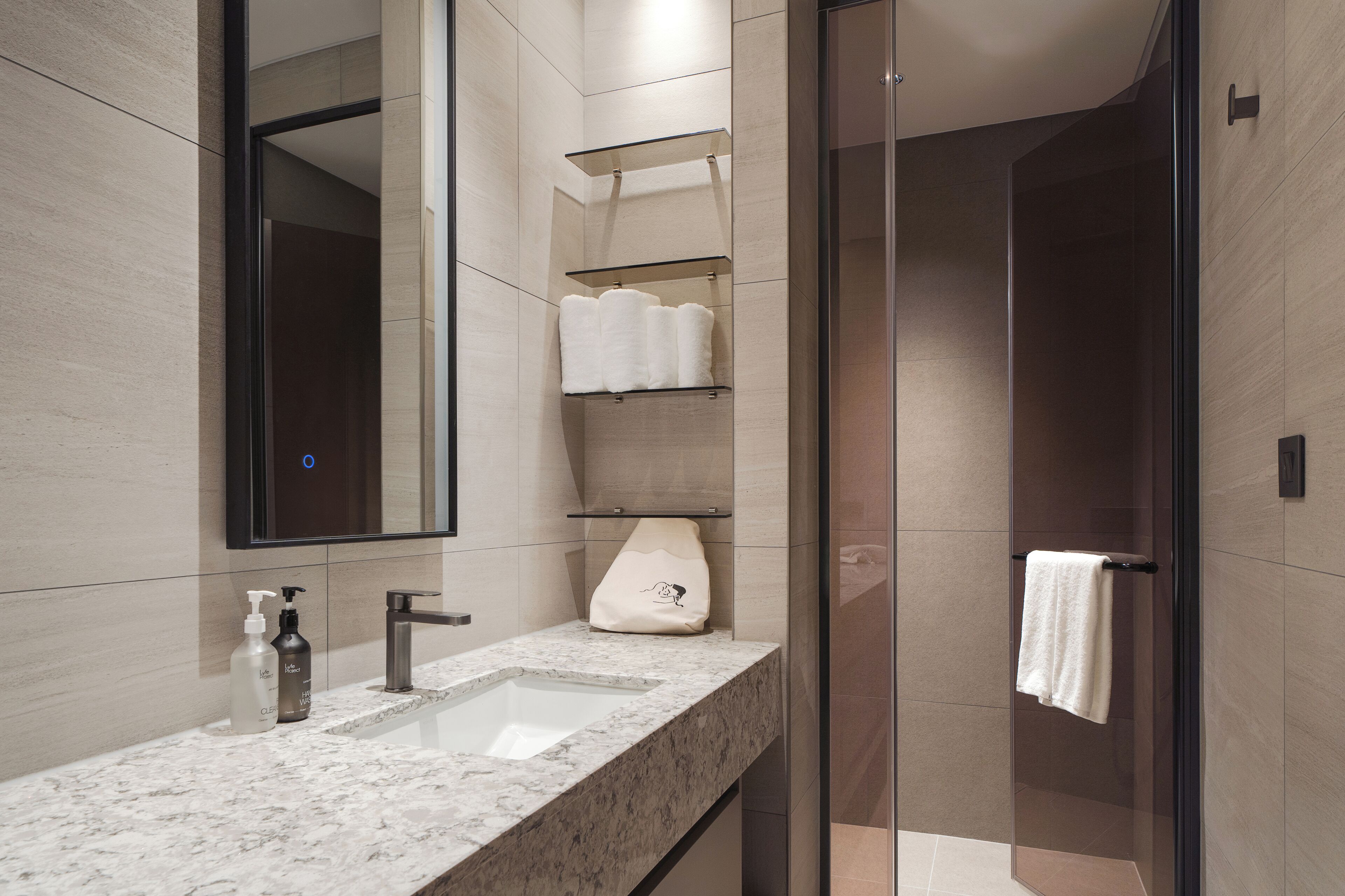 A modern bathroom with a marble sink, a large mirror, and glass shower doors.