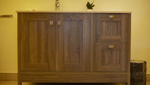 A wooden cabinet with two doors and a drawer, a small plant on top, and a radiator to the right. - Enjoy the Silence Apartments by YourHost (Naivasha)