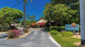 A private property entrance with a sign for Boneyfish Yacht Club, surrounded by lush greenery and a clear sky.