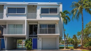 Un edificio de varios pisos con balcones, un garaje y una piscina al fondo.