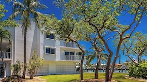 A multi-story hotel with balconies, a pool area, and tropical landscaping.