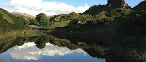 A serene landscape with a calm lake reflecting the sky and surrounding hills.