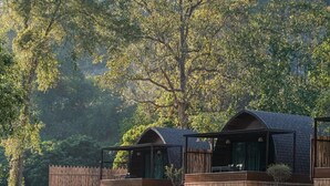 A riverside lodge with wooden cabins, a rocky shoreline, and dense forest in the background. - Pang fan Rock & River Resort (Doi Saket)