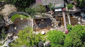 An aerial view of a traditional Japanese garden with a stone bridge, koi ponds, and a wooden walkway. - Pang fan Rock & River Resort (Doi Saket)