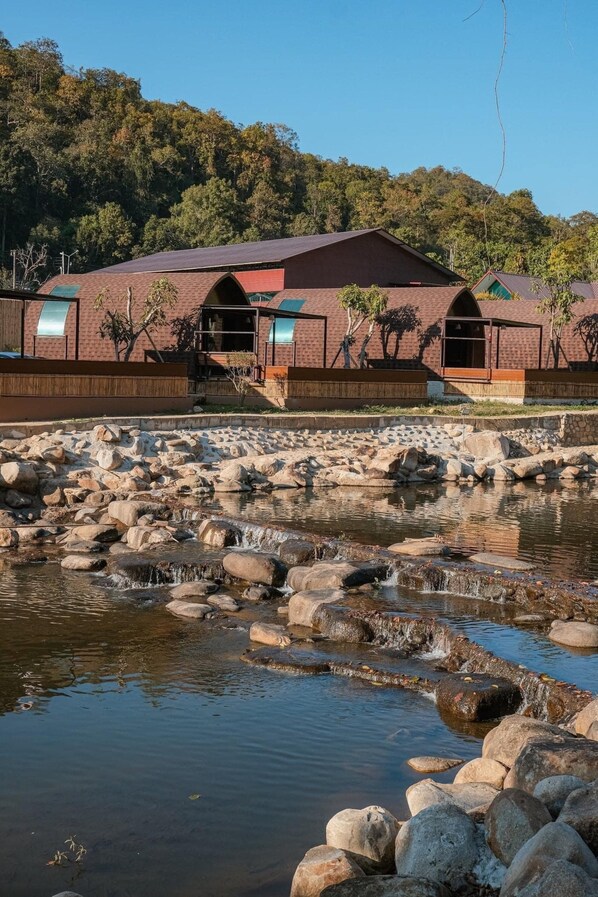 A building with a brick facade and arched windows, situated near a rocky stream. - Pang fan Rock & River Resort (Doi Saket)