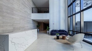 Un interior modern amb una paret de marbre, un sofà, una cadira i una finestra gran.
