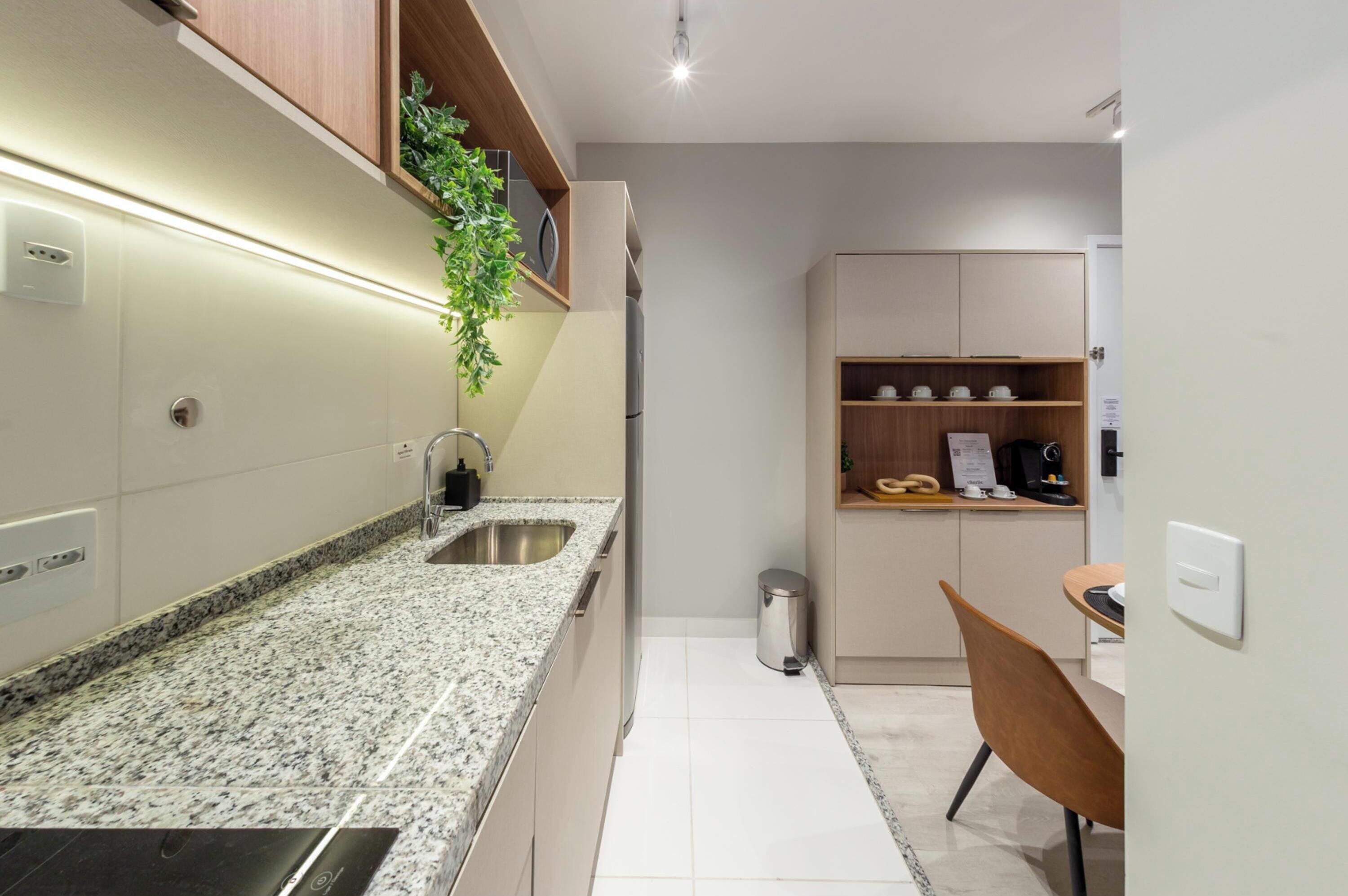 A modern kitchen with granite countertops, a stainless steel sink, and wooden cabinets.