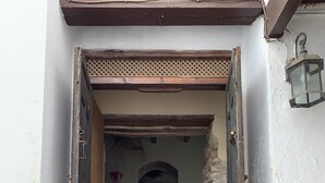 Un vano que da a una habitación con pared de piedra, puerta de madera y suelo de baldosas.