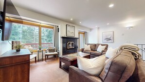 A cozy living room with a fireplace, leather sofa, and a dining area with a small table and chairs. - Pet-Friendly Spacious & Bright Home, Mountain Modern. Walk To The Village (Mammoth Lakes)