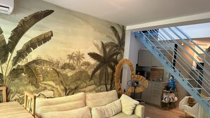 Una sala de estar con un mural grande, un sofá, una mesa de centro y una escalera.