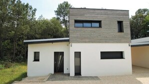 Un edificio moderno a due piani con tetto piatto, un piccolo portico e una strada d'accesso sterrata.