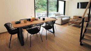 Un soggiorno moderno con un tavolo da pranzo in legno, sedie nere, un divano e una scala.