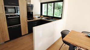 Una cucina moderna con elettrodomestici neri, un tavolo da pranzo in legno e una finestra che si affaccia sul verde.