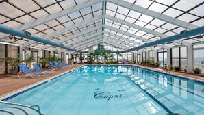 An indoor swimming pool with a glass ceiling, blue lounge chairs, and potted plants. - Beautiful 2 Story Side Ocean View 2 Bed Capri Condo (Ocean City)