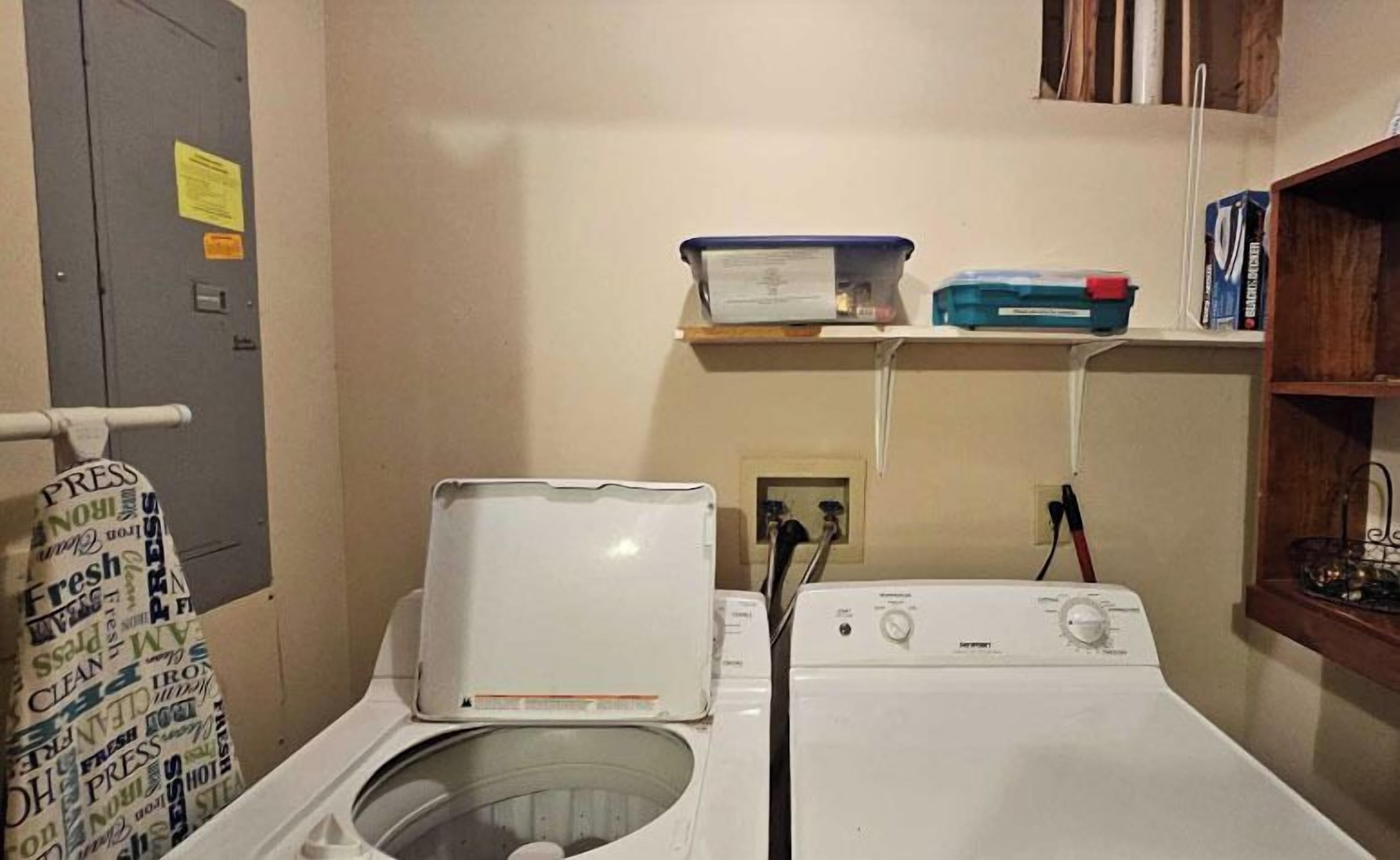 Une buanderie équipée d’un lave-linge et d’un sèche-linge à chargement frontal, d’un porte-serviettes et d’une étagère avec des boîtes de rangement.