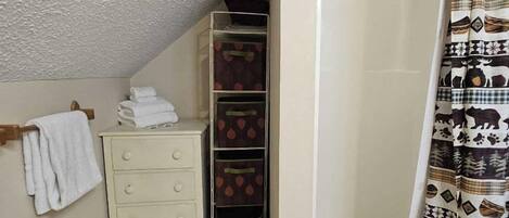 A bathroom with a white cabinet, a towel rack, a shower curtain with animal prints, and a textured ceiling.