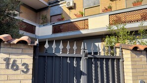 A gated entrance with a number '163' on the wall, a metal gate with finials, and a brick wall. - ISOLA 1.6.3 Guest House (Fiumicino)
