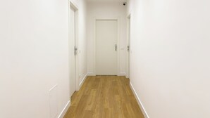 A narrow hallway with wooden flooring and white walls, leading to a closed door at the end. - ISOLA 1.6.3 Guest House (Fiumicino)