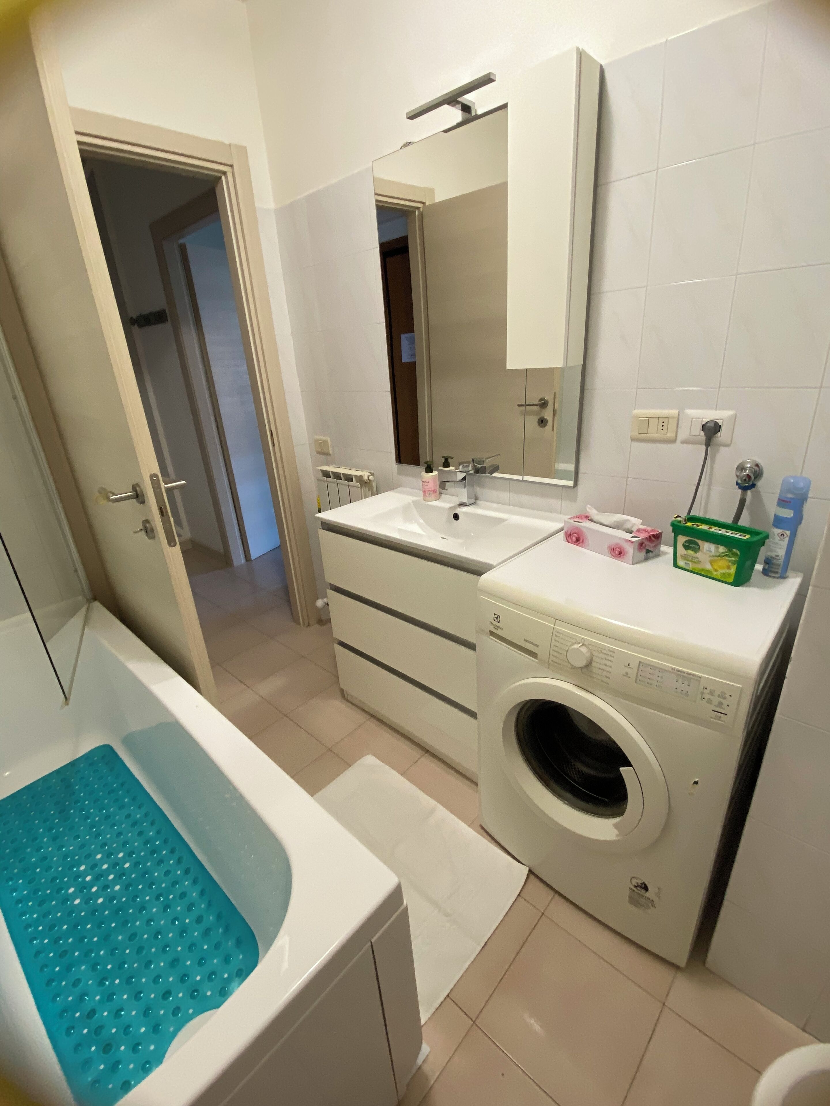 Un bagno con vasca, lavatrice, lavandino e specchio.