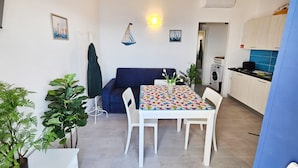 Un espacio habitable compacto con comedor, sofá, lavadora y kitchenette.