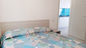 Un dormitorio con cama, cabecera de madera, armario blanco y vista a una piscina por una puerta abierta.