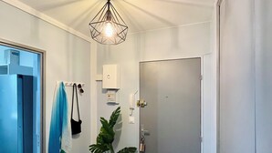 A hallway with a wooden floor, a potted plant, a hanging light fixture, and a door. - Entire rental unit in Maisons-Alfort, France (Maisons-Alfort)