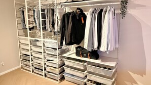 A walk-in closet with multiple shelves and drawers for storage, featuring hanging clothes and shoes. - Elevate Suite 360° (Trier)