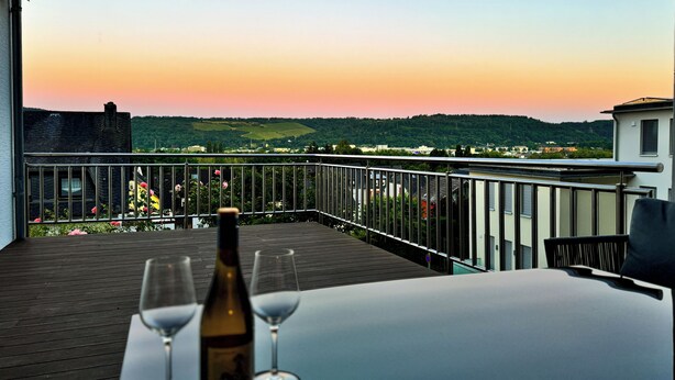 A balcony with a table, two wine glasses, and a bottle of wine. - Elevate Suite 360° (Trier)