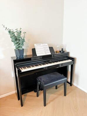 Un piano con partituras, una planta en maceta y un banco.