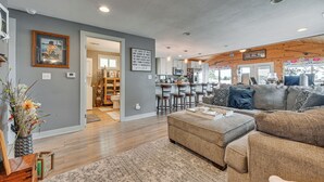 A modern living room with a grey sofa, a coffee table, and a dining area with bar stools. - Angler's Cottage on Lake Cornelia: Pets Welcome! (Clarion)