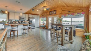 A spacious kitchen with wooden cabinets, a central island, and bar stools. - Angler's Cottage on Lake Cornelia: Pets Welcome! (Clarion)