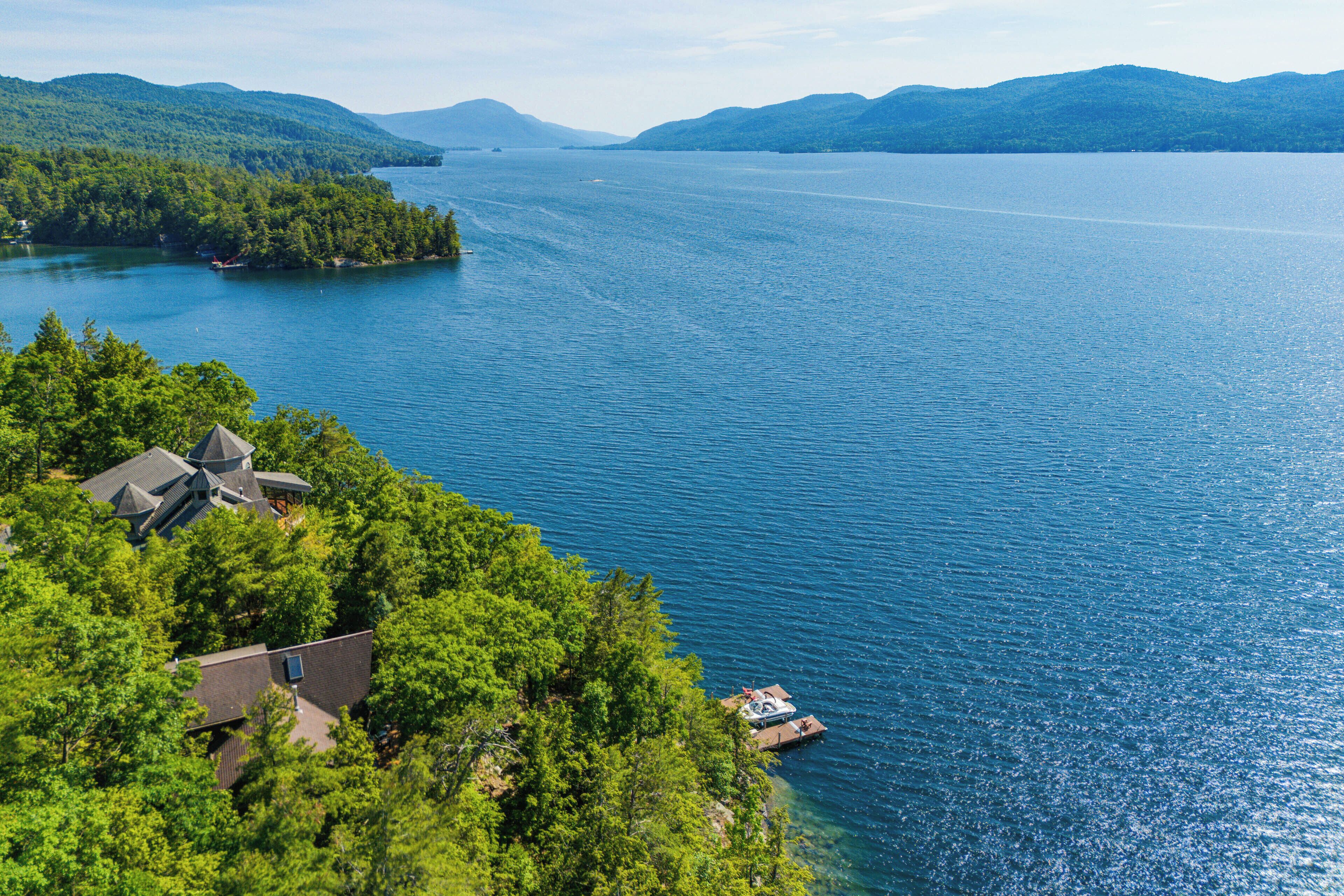 A lakeside property with a boat dock, surrounded by dense forest and hills.