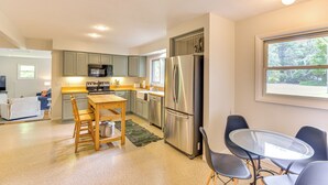 A modern kitchen with a stainless steel refrigerator, wooden dining table, and chairs. - Charming Union Pier Home w/ Deck: Half-mi to Beach (Union Pier)